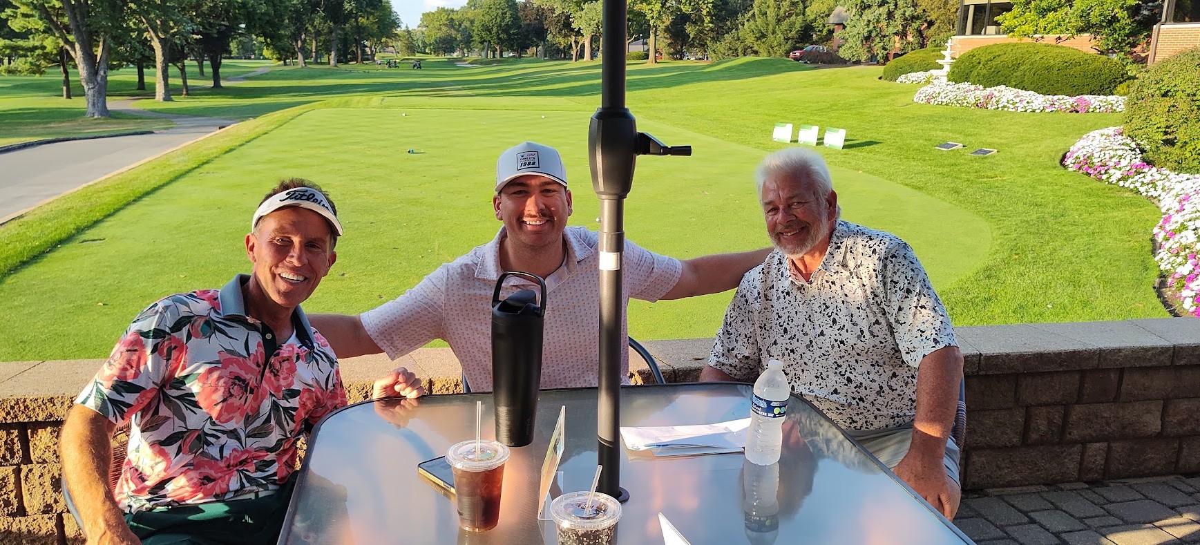 Irish-Classic-25-golfers-with-putting-greenCROPPED (1) Group of three golfers sitting at a table